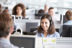 Young woman working in call centre, surrounded by colleagues - Gemstone Logistics